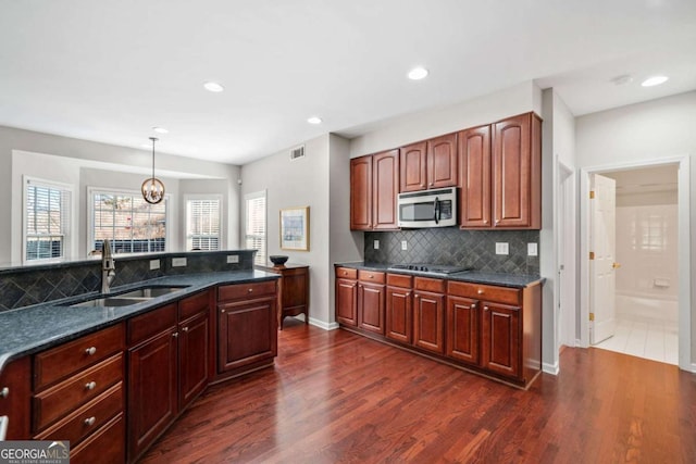 kitchen with decorative light fixtures, black electric stovetop, visible vents, stainless steel microwave, and a sink