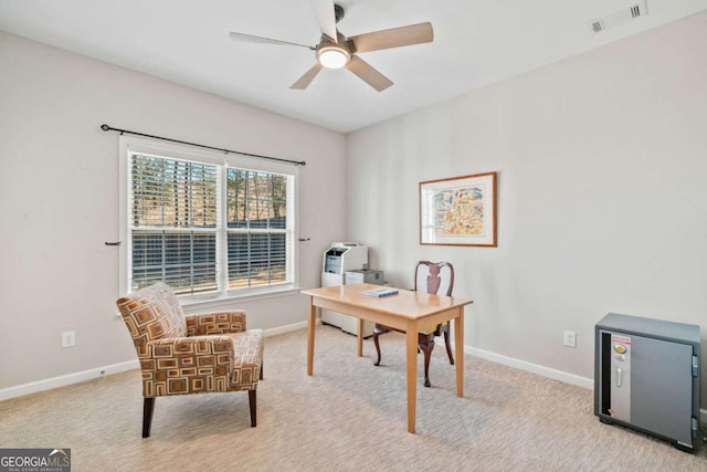 office space with a ceiling fan, visible vents, light carpet, and baseboards