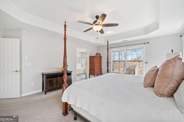 bedroom featuring light carpet, baseboards, a tray ceiling, and connected bathroom