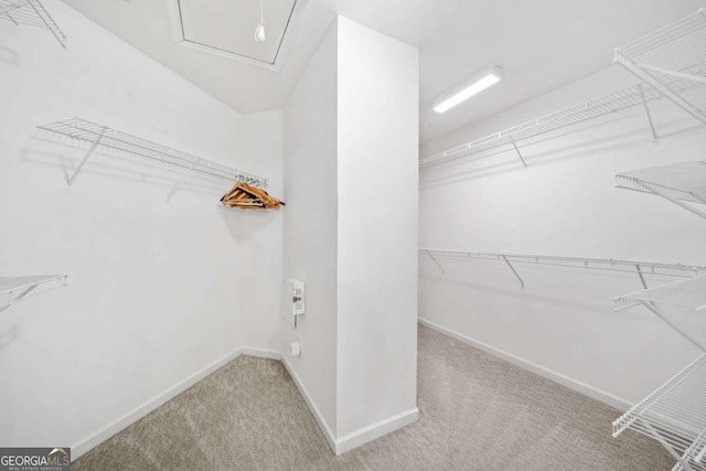 spacious closet with attic access and light carpet