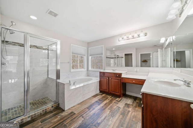 bathroom with a garden tub, visible vents, a stall shower, vanity, and wood finished floors