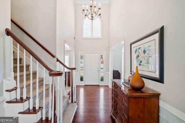 entrance foyer with baseboards, dark wood-style floors, stairway, a high ceiling, and a notable chandelier