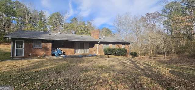 rear view of house featuring brick siding, a lawn, and a chimney