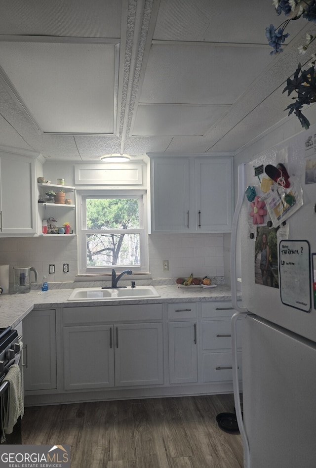 kitchen with a sink, backsplash, freestanding refrigerator, range, and dark wood-style flooring