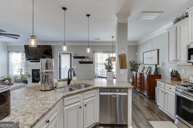 kitchen featuring a sink, white cabinets, open floor plan, appliances with stainless steel finishes, and light stone countertops