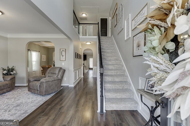 entrance foyer with dark wood-style floors, arched walkways, visible vents, and ornamental molding