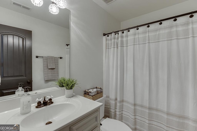 full bath with toilet, vanity, and visible vents