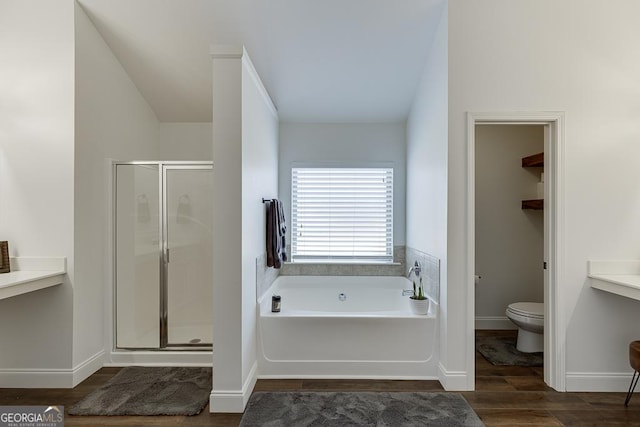 bathroom with toilet, a stall shower, a bath, and wood finished floors