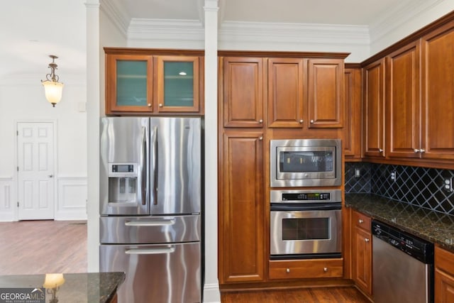 kitchen featuring dark stone counters, appliances with stainless steel finishes, dark wood finished floors, and ornamental molding