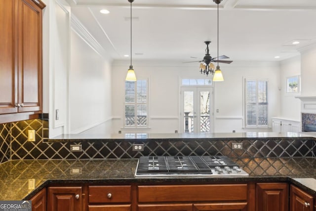 kitchen featuring ceiling fan, stainless steel gas stovetop, ornamental molding, and decorative backsplash