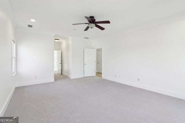 spare room with a ceiling fan, light carpet, crown molding, and baseboards