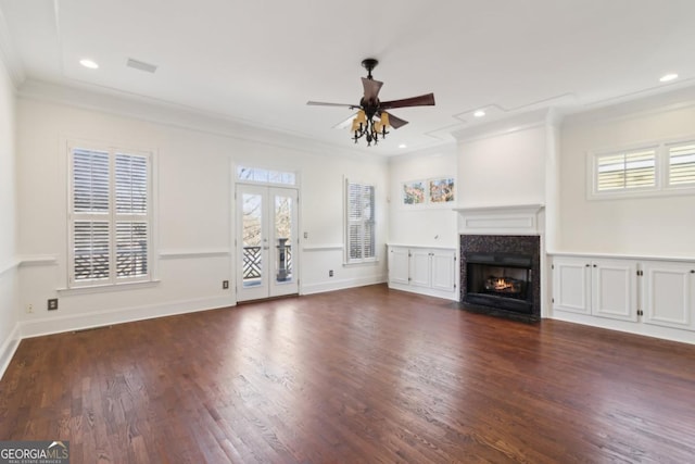 unfurnished living room with dark wood-type flooring, a fireplace with flush hearth, a ceiling fan, french doors, and crown molding