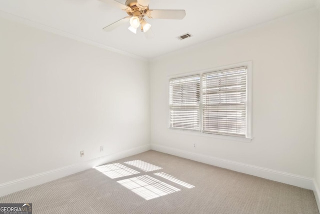 unfurnished room with ceiling fan, light carpet, visible vents, baseboards, and ornamental molding