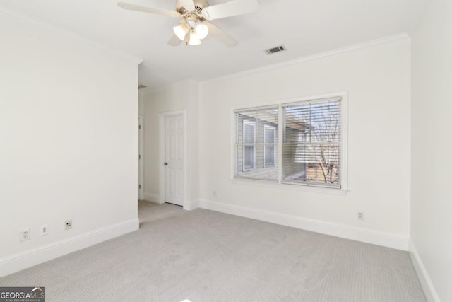 empty room featuring ornamental molding, light colored carpet, visible vents, and baseboards