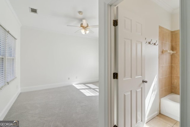 interior space with baseboards, visible vents, a ceiling fan, ornamental molding, and tile patterned floors