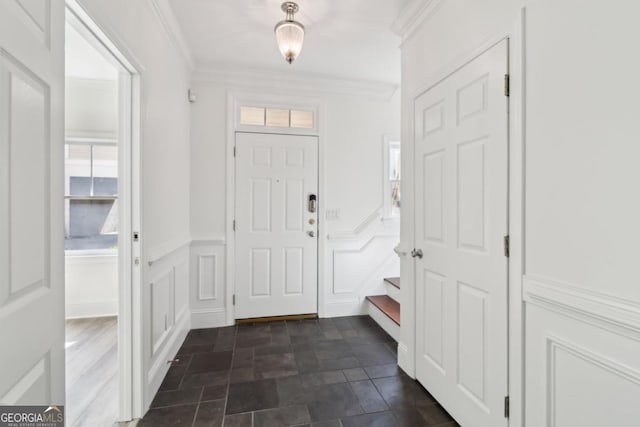 foyer entrance featuring a wainscoted wall, crown molding, and a decorative wall