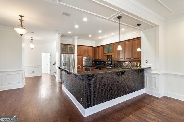 kitchen featuring stainless steel appliances, a sink, ornamental molding, backsplash, and brown cabinetry