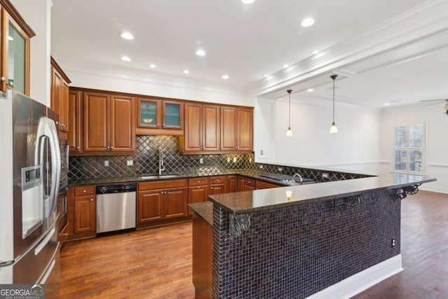 kitchen with stainless steel appliances, brown cabinetry, a sink, and dark wood-style floors