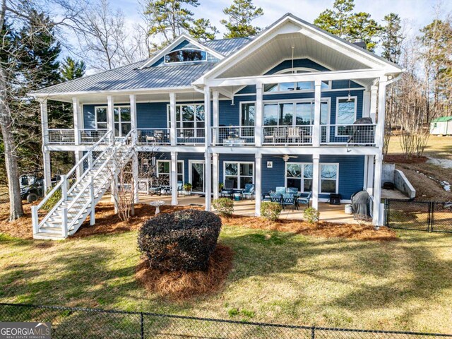 back of property with a patio area, stairway, metal roof, and a yard