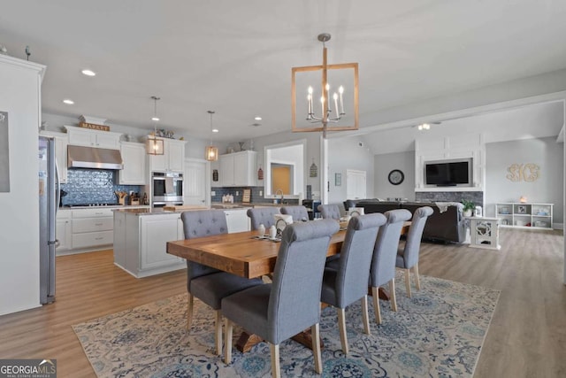 dining room featuring lofted ceiling, recessed lighting, light wood-type flooring, and an inviting chandelier