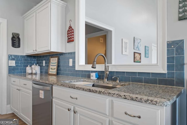 kitchen with light stone counters, backsplash, stainless steel dishwasher, white cabinets, and a sink