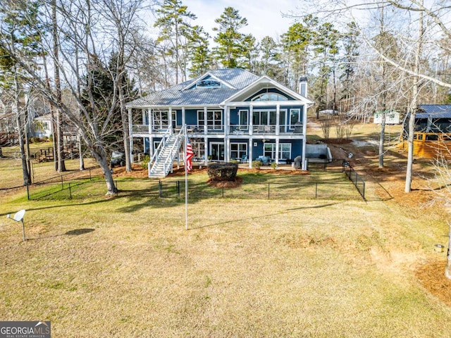 view of front of property featuring stairs, metal roof, a front lawn, and fence