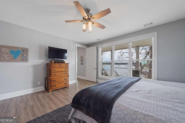 bedroom featuring a ceiling fan, visible vents, baseboards, and wood finished floors