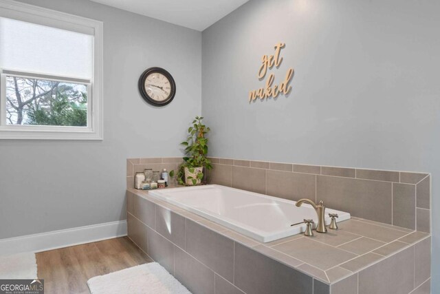 bathroom featuring a garden tub, baseboards, and wood finished floors