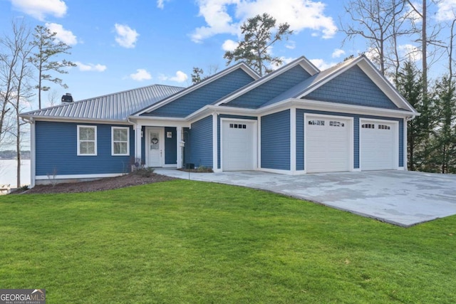 view of front of property featuring a garage, driveway, metal roof, and a front yard