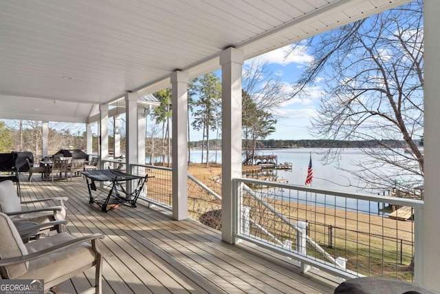 wooden terrace with a water view and outdoor dining space