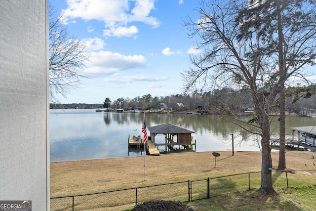 dock area with a water view, a yard, and fence