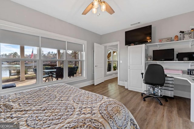 bedroom featuring built in desk, visible vents, ceiling fan, wood finished floors, and baseboards