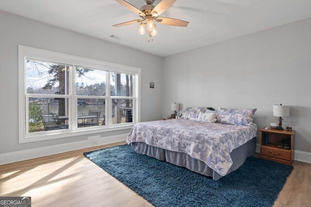 bedroom with ceiling fan, wood finished floors, visible vents, and baseboards