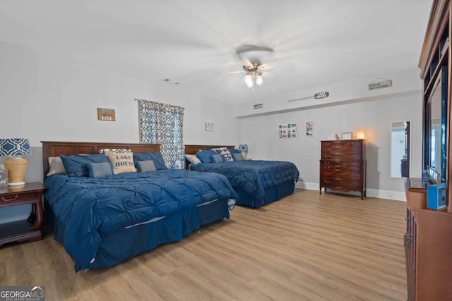 bedroom with light wood-type flooring, ceiling fan, visible vents, and baseboards