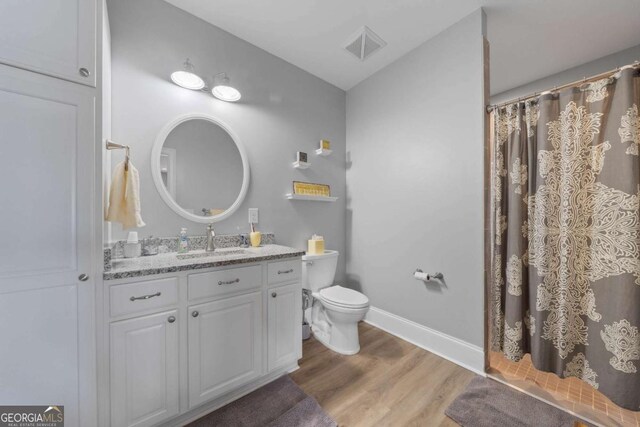 bathroom featuring toilet, wood finished floors, visible vents, vanity, and baseboards