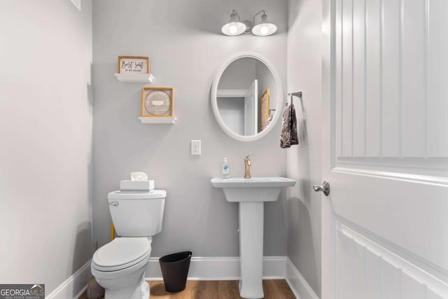 bathroom with toilet, baseboards, and wood finished floors