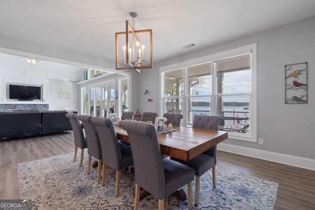 dining space with wood finished floors, visible vents, baseboards, and an inviting chandelier