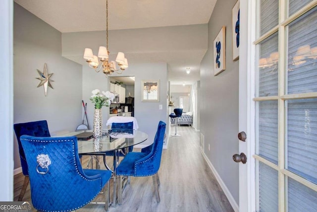 dining room featuring a chandelier, wood finished floors, and baseboards