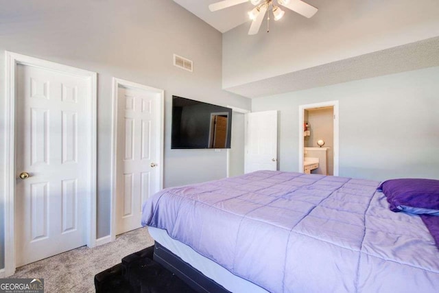 bedroom with lofted ceiling, light colored carpet, visible vents, a ceiling fan, and ensuite bath