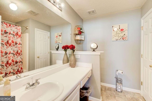 bathroom featuring a textured ceiling, vanity, visible vents, and baseboards