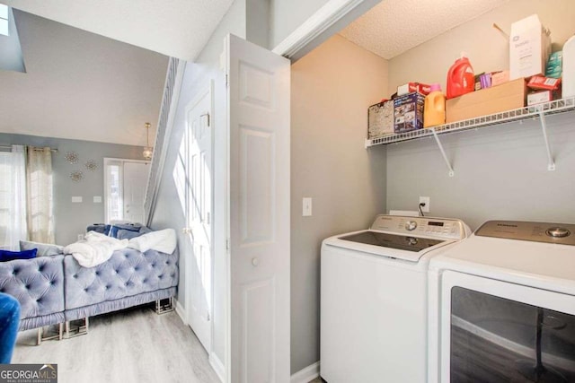 clothes washing area featuring laundry area, washing machine and dryer, light wood-style flooring, and baseboards