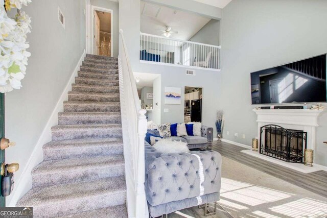 stairway featuring a fireplace, visible vents, ceiling fan, wood finished floors, and baseboards