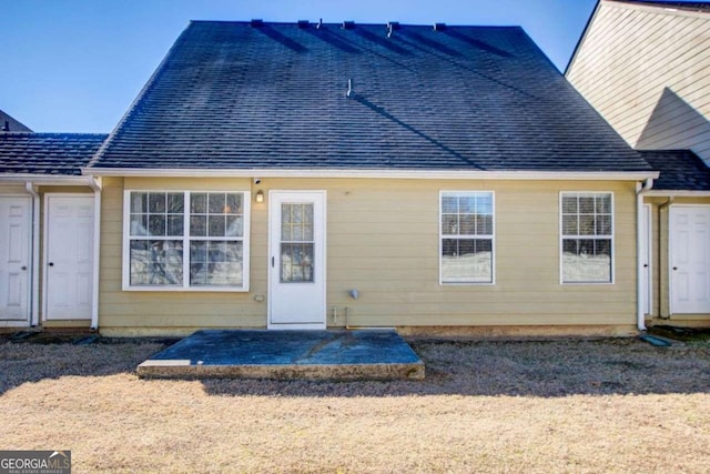 rear view of house featuring a patio and roof with shingles