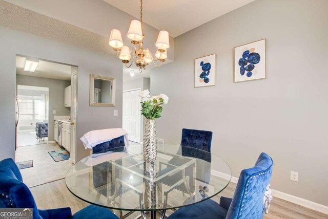 dining space featuring an inviting chandelier, baseboards, and light wood-style floors