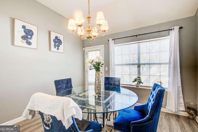 dining space featuring a chandelier, wood finished floors, and baseboards