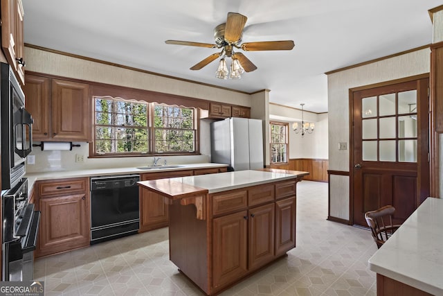 kitchen with black dishwasher, light countertops, wainscoting, freestanding refrigerator, and a center island