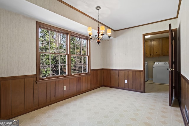 spare room featuring a wainscoted wall, a notable chandelier, light floors, ornamental molding, and washer and dryer