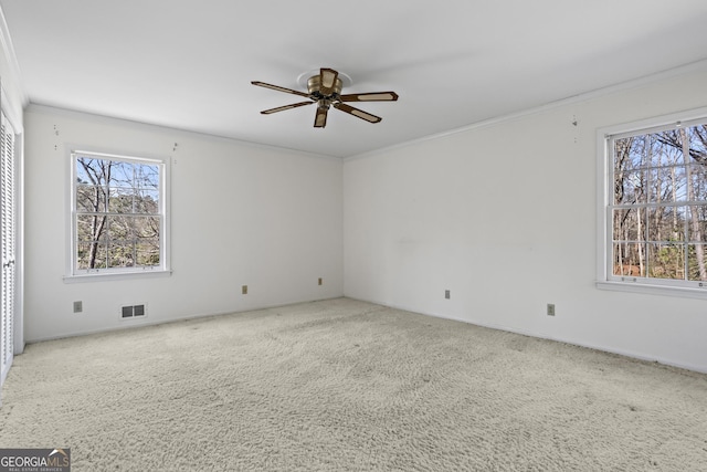 carpeted empty room featuring a wealth of natural light, crown molding, and ceiling fan