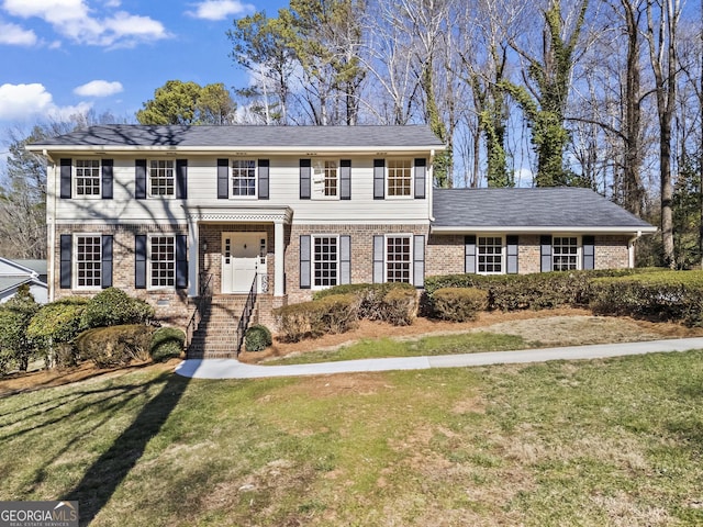 colonial home featuring a front yard and brick siding