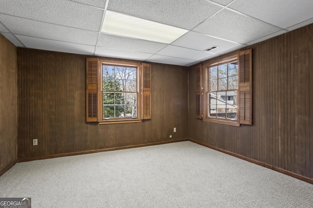 spare room with wood walls, carpet, and visible vents